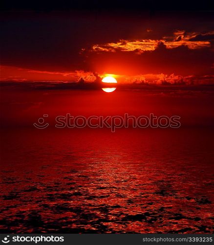 dramatic bloody sunrise on dark sky over sea