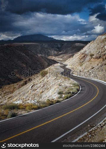 Dramatic cloudscape over empty road through scenic canyon, Santa Rosalia, Baja California, Mexico
