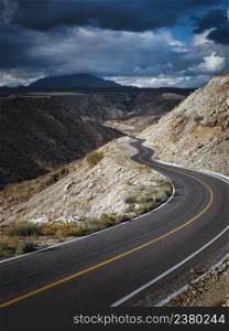 Dramatic cloudscape over empty road through scenic canyon, Santa Rosalia, Baja California, Mexico