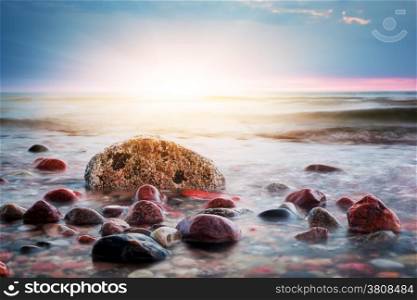 Dramatic colorful sunset on a rocky beach. Baltic sea. Seascape theme