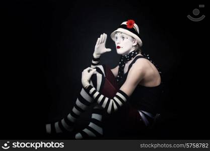 Dramatic funny mime in white hat on black background
