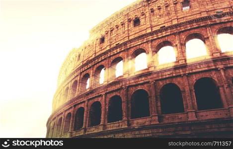 dramatic image of the Colosseum of Rome during sunset with sun rays filtering through the arches