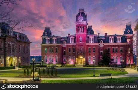 Dramatic image of Woodburn Hall at West Virginia University or WVU in Morgantown WV as the sun sets behind the illuminated historic building. Woodburn Hall at West Virginia University in Morgantown WV