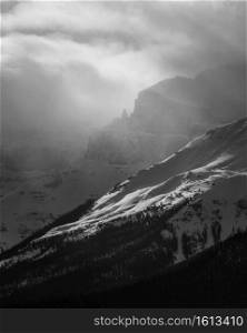 Dramatic light streaming through atmospheric conditions in the Canadian Rockies during the Winter in black and white.