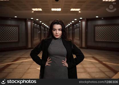 dramatic portrait of a beautiful young woman in a black coat in an underground passage.mosaics on the walls are not someone&rsquo;s works of art.these are walls in an underground passage in Eastern style