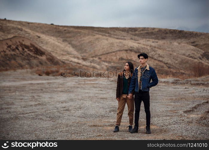 Dramatic portrait of a young brunette girl and a guy in cloudy weather. selective focus, small focus area
