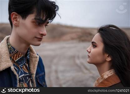 Dramatic portrait of a young brunette girl and a guy in cloudy weather.they look into each other&rsquo;s eyes . selective focus, small focus area