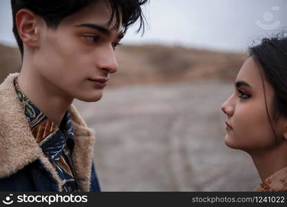 Dramatic portrait of a young brunette girl and a guy in cloudy weather.they look into each other&rsquo;s eyes . selective focus, small focus area