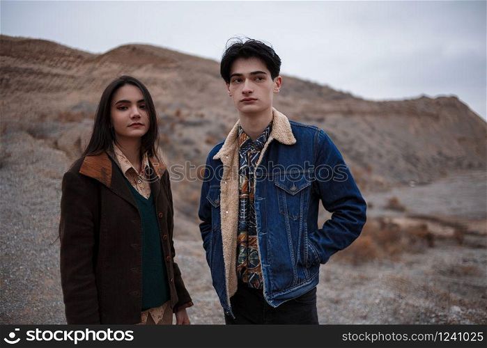 Dramatic portrait of a young brunette girl and a guy in cloudy weather. selective focus, small focus area