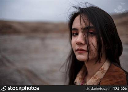 Dramatic portrait of a young brunette girl in cloudy weather against the background of mountains