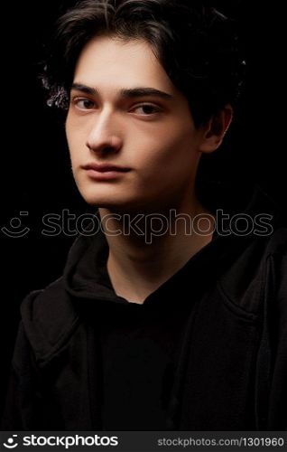 dramatic portrait of a young man in black clothes on a black background