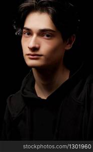 dramatic portrait of a young man in black clothes on a black background
