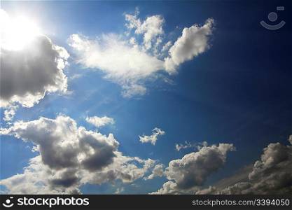 dramatic scene with clouds and sun on blue sky