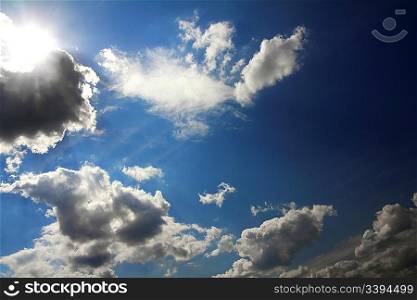 dramatic scene with clouds and sun on blue sky