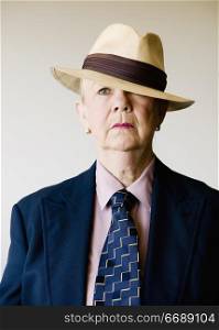 Dramatic senior woman in a man&acute;s suit wearing a straw gangster hat