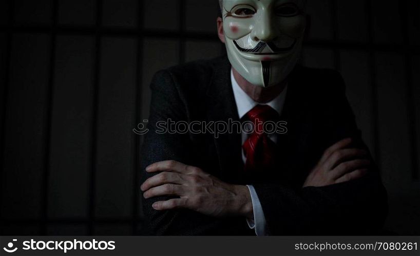 Dramatic shot of Anonymous hacker in prison