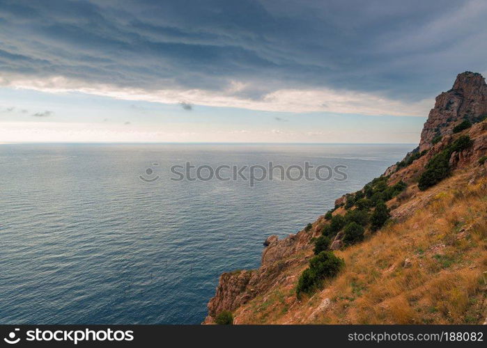 Dramatic sky, rocky coast and calm sea before the storm