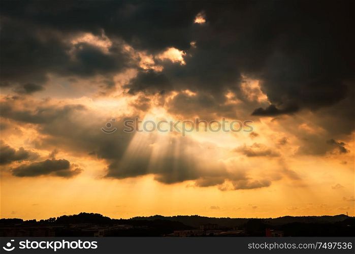 Dramatic sunlight or sun ray through the clouds at sunset sky background .