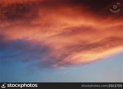Dramatic sunset landscape with puffy clouds lit by orange setting sun and blue sky. Dramatic sunset landscape with puffy clouds lit by orange setting sun and blue sky.