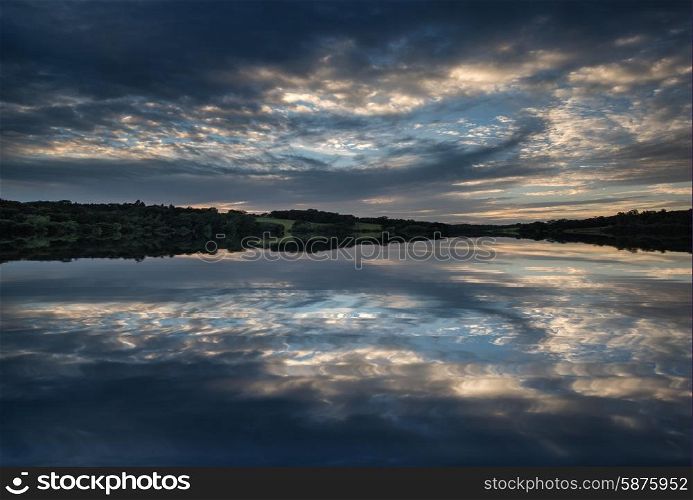 Dramatic sunset over calm lake in Summer in English countryside