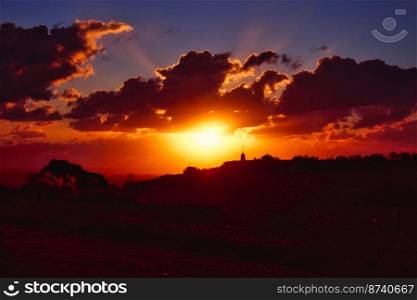 Dramatic sunset scene over hills in the countryside with deep shades of orange, red and blue