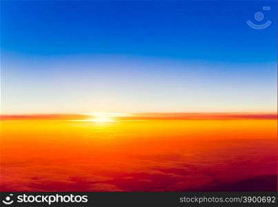 Dramatic sunset. View of sunset above clouds from airplane window
