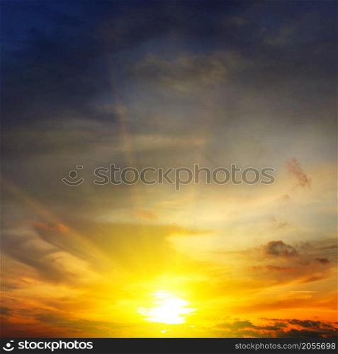 Dramatic sunset with bright rays and clouds in sky.