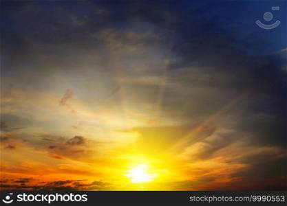 Dramatic sunset with bright rays and dark clouds in sky.