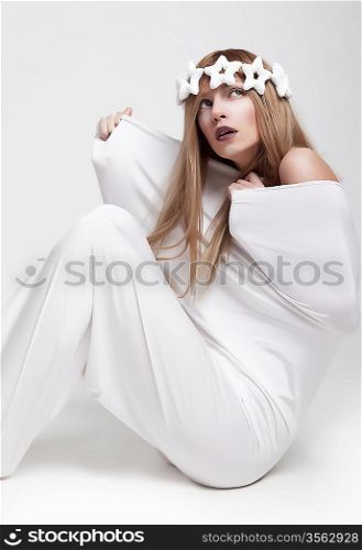 Dramatic theatrical pose - young girl actress in white crown and clothes sitting. Series of photos