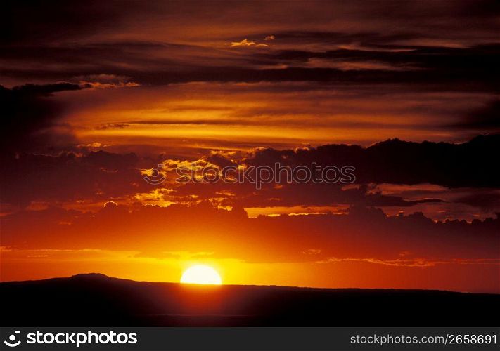 Dramatic yellow sky and sun setting over distant hill