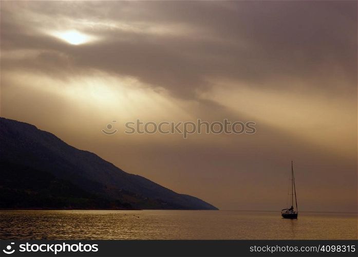 dramatically beautiful landscape with sea, ship and sun covered with clouds