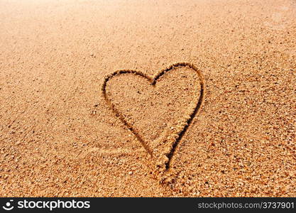 drawing a heart on the wet sand at the sea