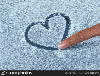 Drawing a snow heart with a finger as a fun winter love symbol as a romantic shape valentine greetings on a cold weather frosty surface.