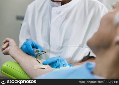 Drawing Blood for Platelet Rich Plasma face treatment.  Doctor’s hand in blue surgical glove drawing blood for PRP face cosmetics treatment. 