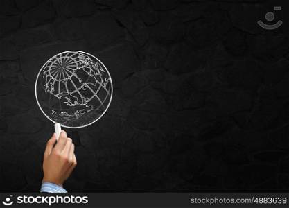 Drawing globe . Close up of hand drawing globe on blackboard