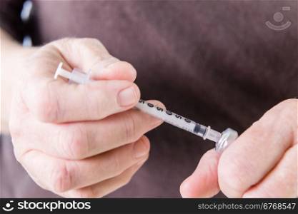 Drawing insulin from vial with syringe