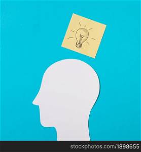 drawn light bulb icon sticky note paper cut out head against blue background. Resolution and high quality beautiful photo. drawn light bulb icon sticky note paper cut out head against blue background. High quality beautiful photo concept