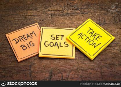 dream big, set goals, take action - motivational advice or reminder on colorful sticky notes against rustic wood