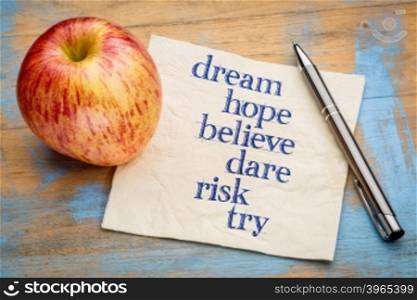dream, hope, believe, dare, risk and try - handwriting on a napkin with a fresh apple