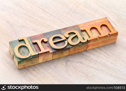 dream word abstract in letterpress wood type against grained wood