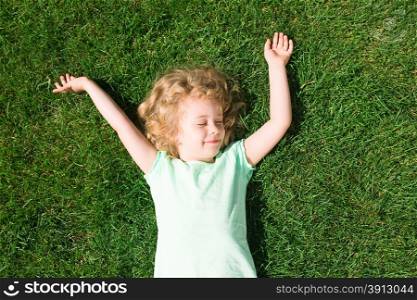 Dreaming adorable girl lying on grass, top view