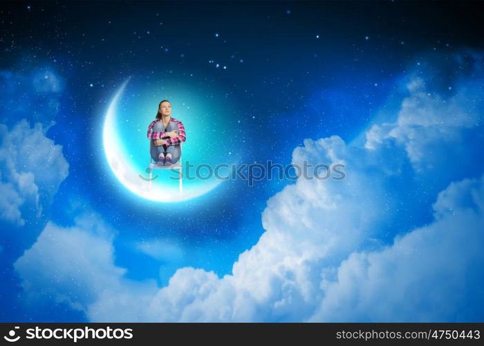 Dreaming at night. Young pretty girl sitting on moon in sky