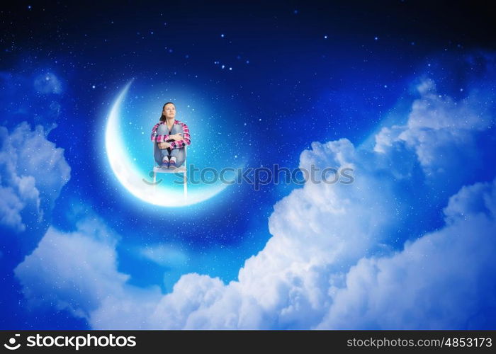 Dreaming at night. Young pretty girl sitting on moon in sky