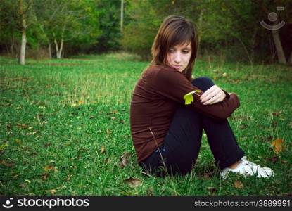 Dreaming girl sits on green field