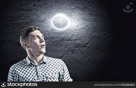 Dreaming man. Young man and moon planet against dark background