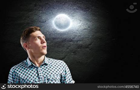 Dreaming man. Young man and moon planet against dark background