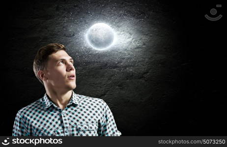 Dreaming man. Young man and moon planet against dark background