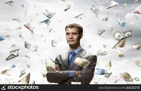 Dreaming to become rich. Young businessman standing in the rain of money banknotes