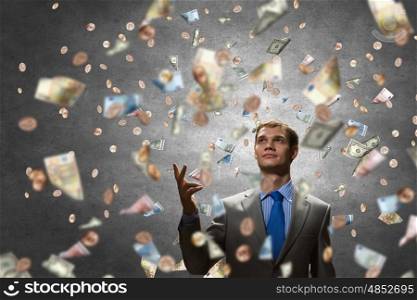 Dreaming to become rich. Young businessman standing in the rain of money banknotes