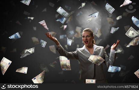 Dreaming to become rich. Young businesswoman standing in the rain of money banknotes